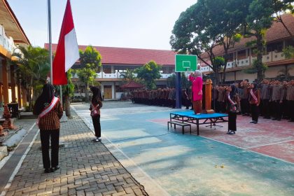 Dessy Prastianti Dewi, S.Pd. sebagai pembina upacara yang mengenakan kebaya pink fanta mencolok di atas panggung.