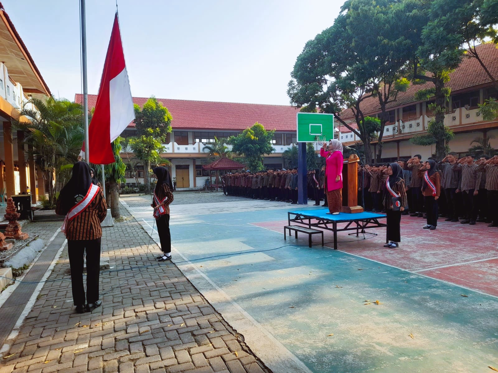 Dessy Prastianti Dewi, S.Pd. sebagai pembina upacara yang mengenakan kebaya pink fanta mencolok di atas panggung.